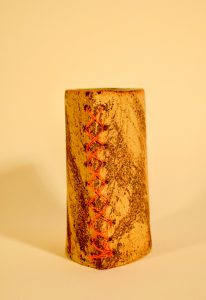 Thin oval vase, iron oxide in the texture and orange fishing line sewn at the ends