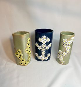 Vases with daisy or sunflower sprigs decorating them