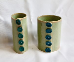 Two green round vases that look like they are fastened with blue or turquoise buttons